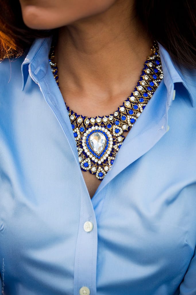 woman wearing a bright blue dress and a statement necklace.