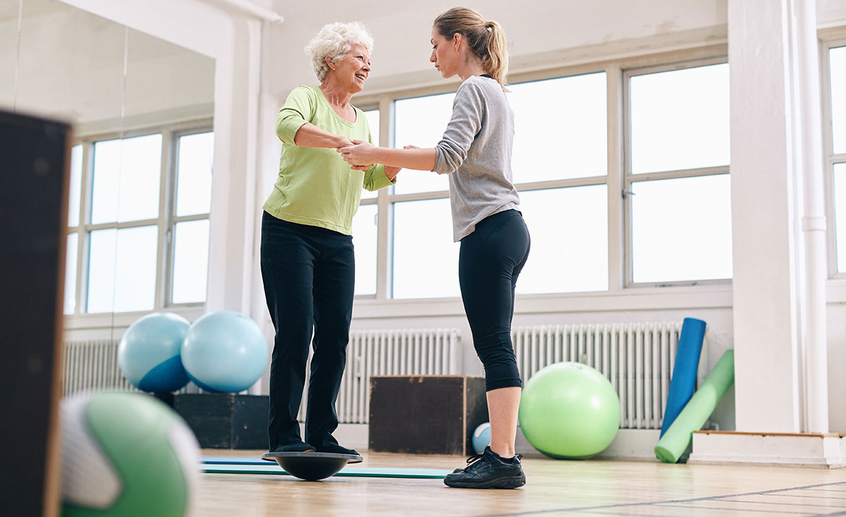 An elderly person performing balance exercises under the guidance of a physical therapist.