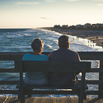 Elderly Couple Sitting on a bench watching sunset