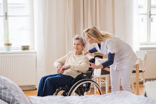 An elderly individual receiving training on how to use a mobility aid from a healthcare professional.