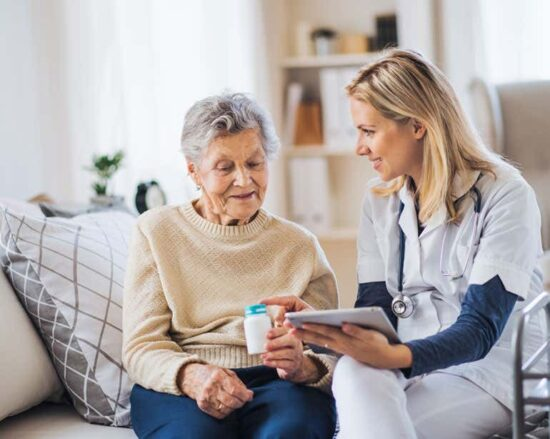 A senior citizen checking her medication with a caregiver