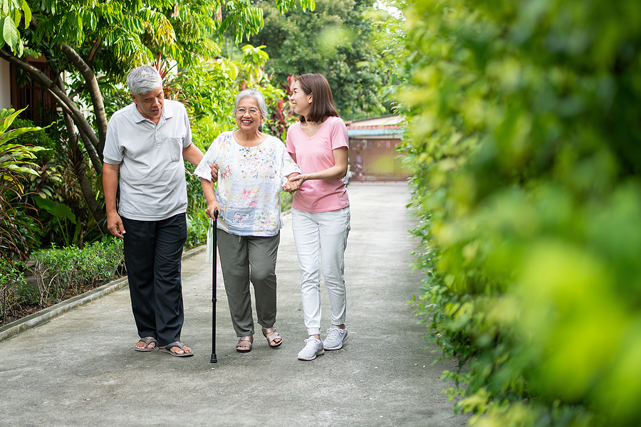 family providing support to a senior during a walk.